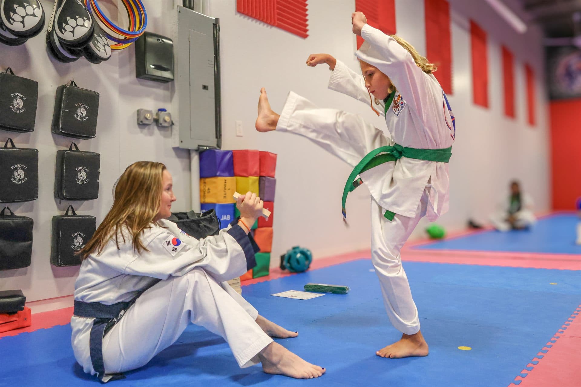 Student performing a flying kick to a board